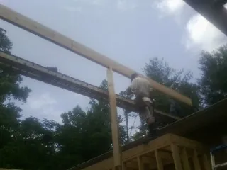Carpenter setting a ridge beam over a new addition frame — Ice Dam Removal by Roofing Brothers in Homer City