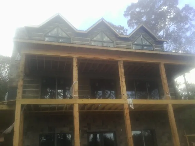 Dormers and porch framing on a large log home under construction — Roof Coating work by our crew in Homer City