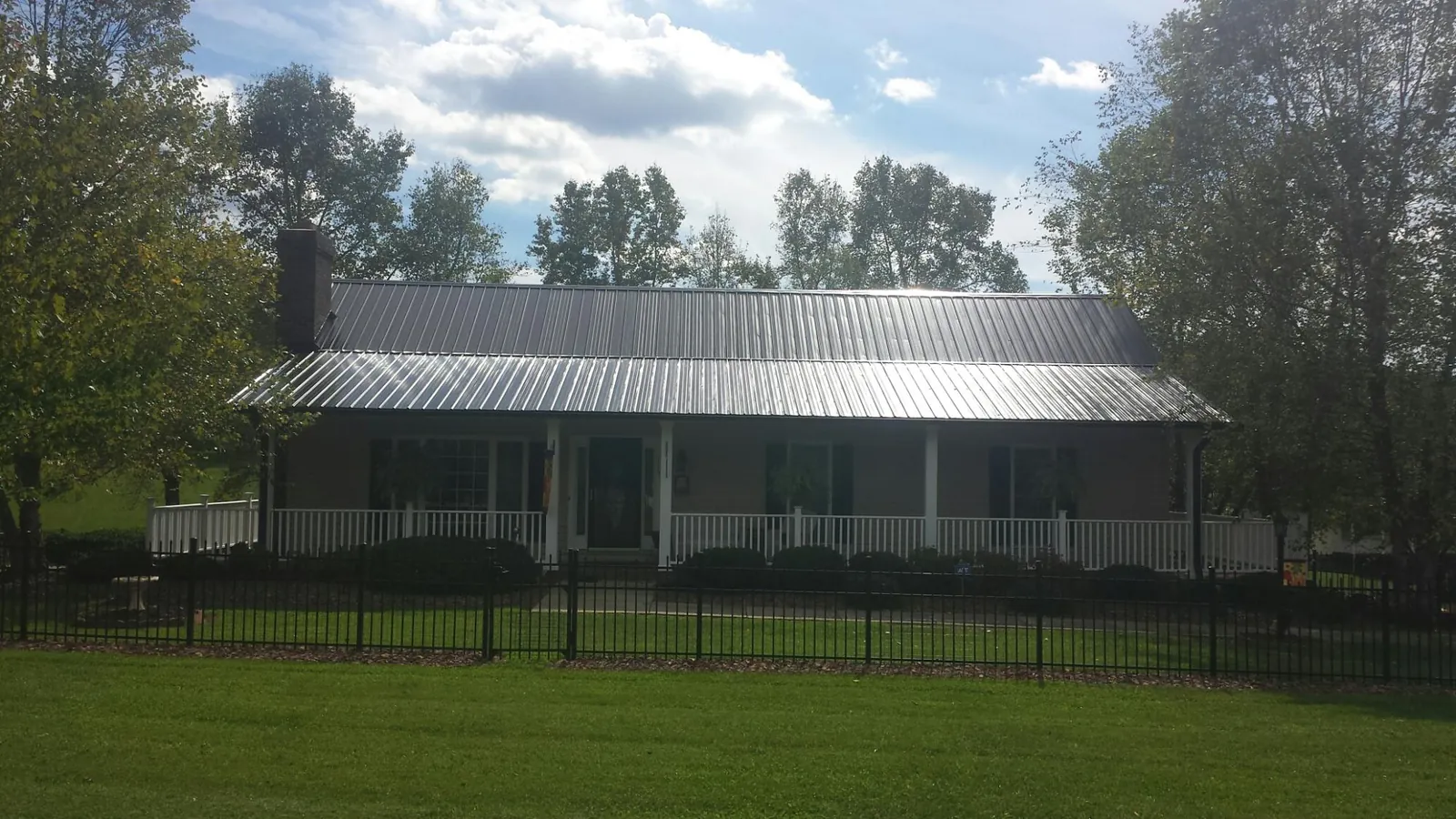 Gray metal roof on a brick ranch with a full width front porch — Gutter Guard Installation work by our crew in Homer City