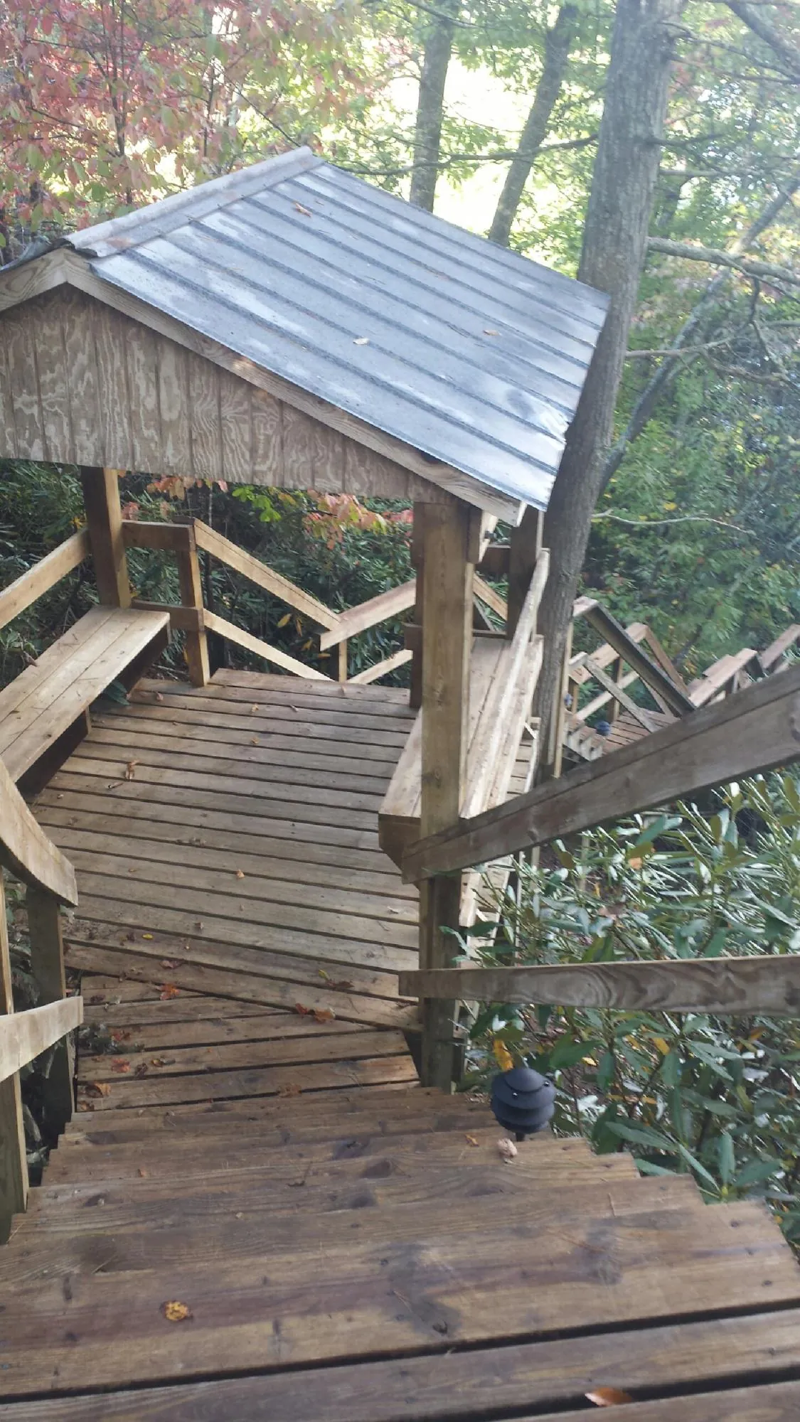 Metal roofed shelter over wooden steps on a wooded walkway — Skylight Repair & Installation work by our crew in Homer City