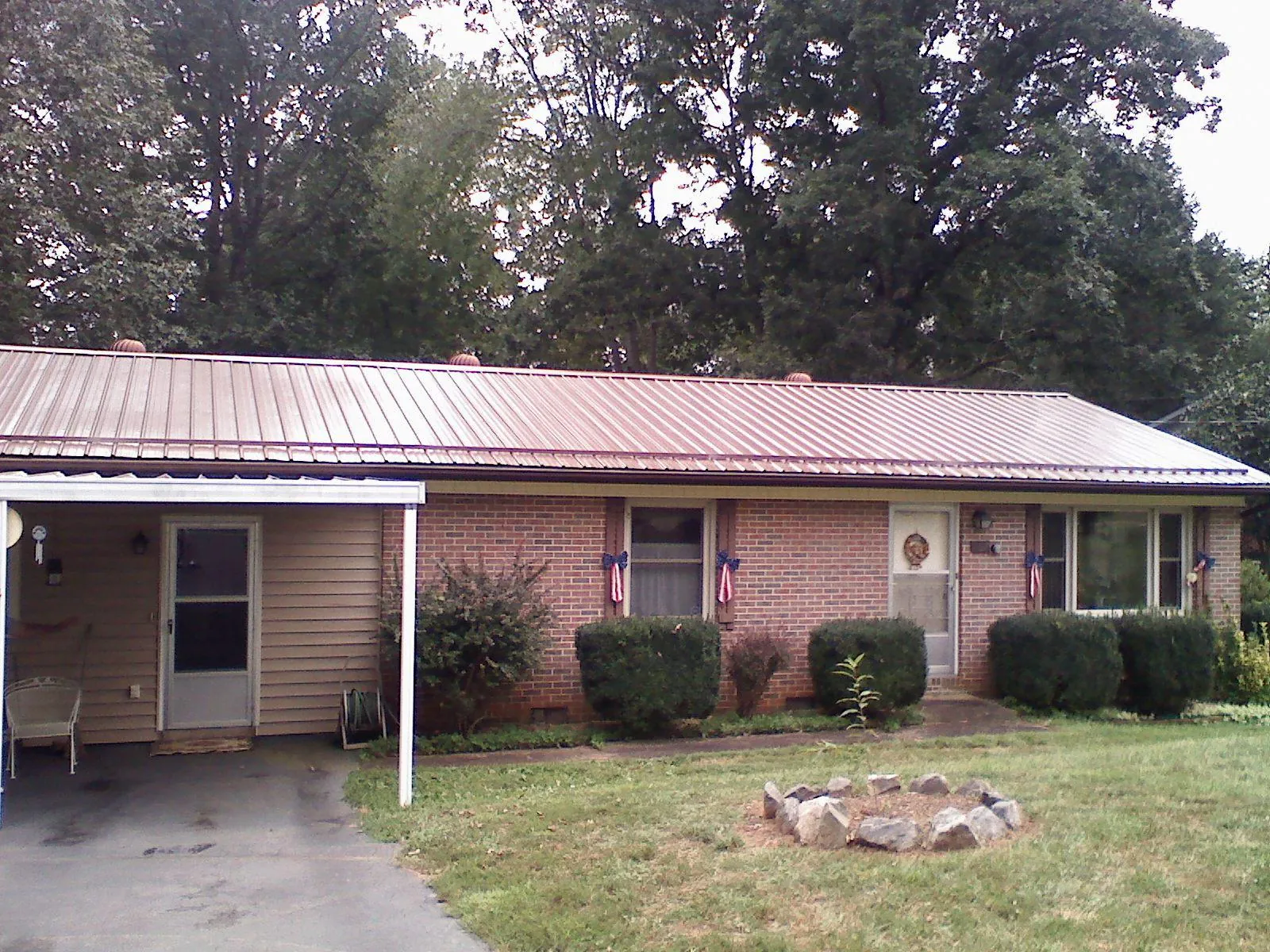 Bronze metal roof and carport on a brick ranch home — Roof Repair work by our crew in Homer City