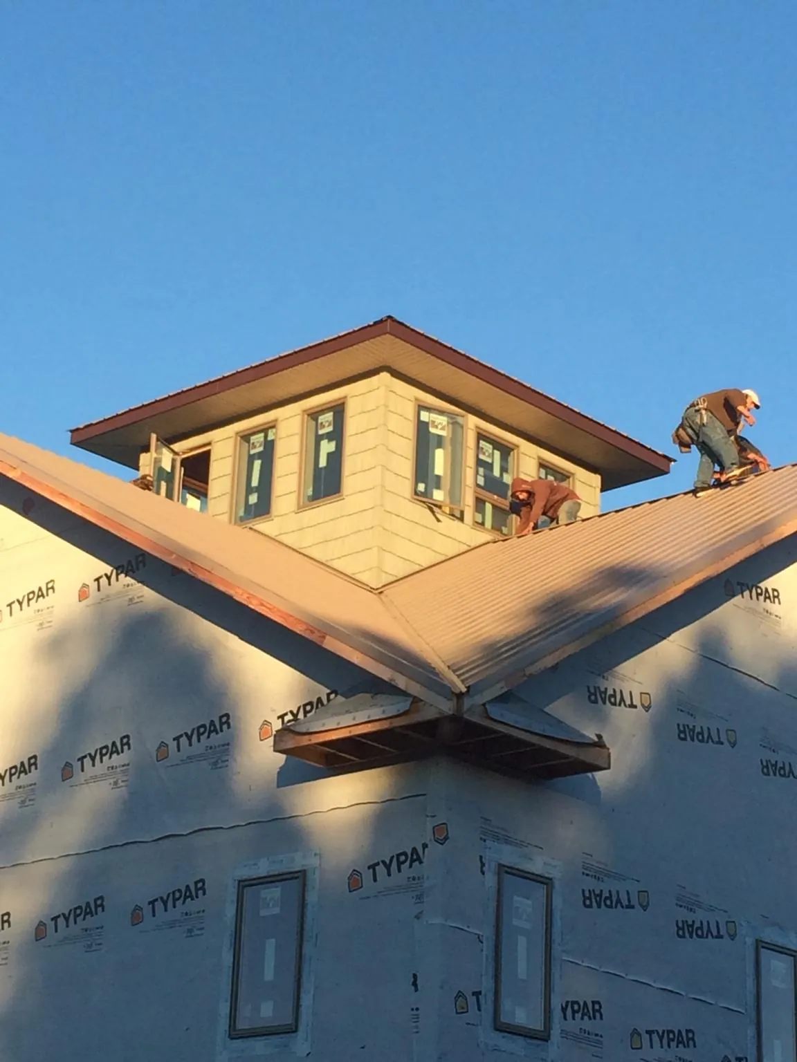 Roofers working around a rooftop cupola on a new metal roof at sunset — Roof Waterproofing in Homer City by Roofing Brothers